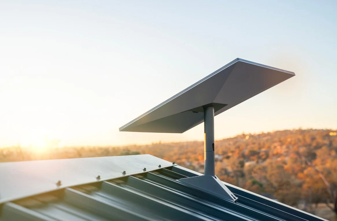 Close-up of a Starlink Standard a on a rooftop during sunset with a hilly landscape in the background.