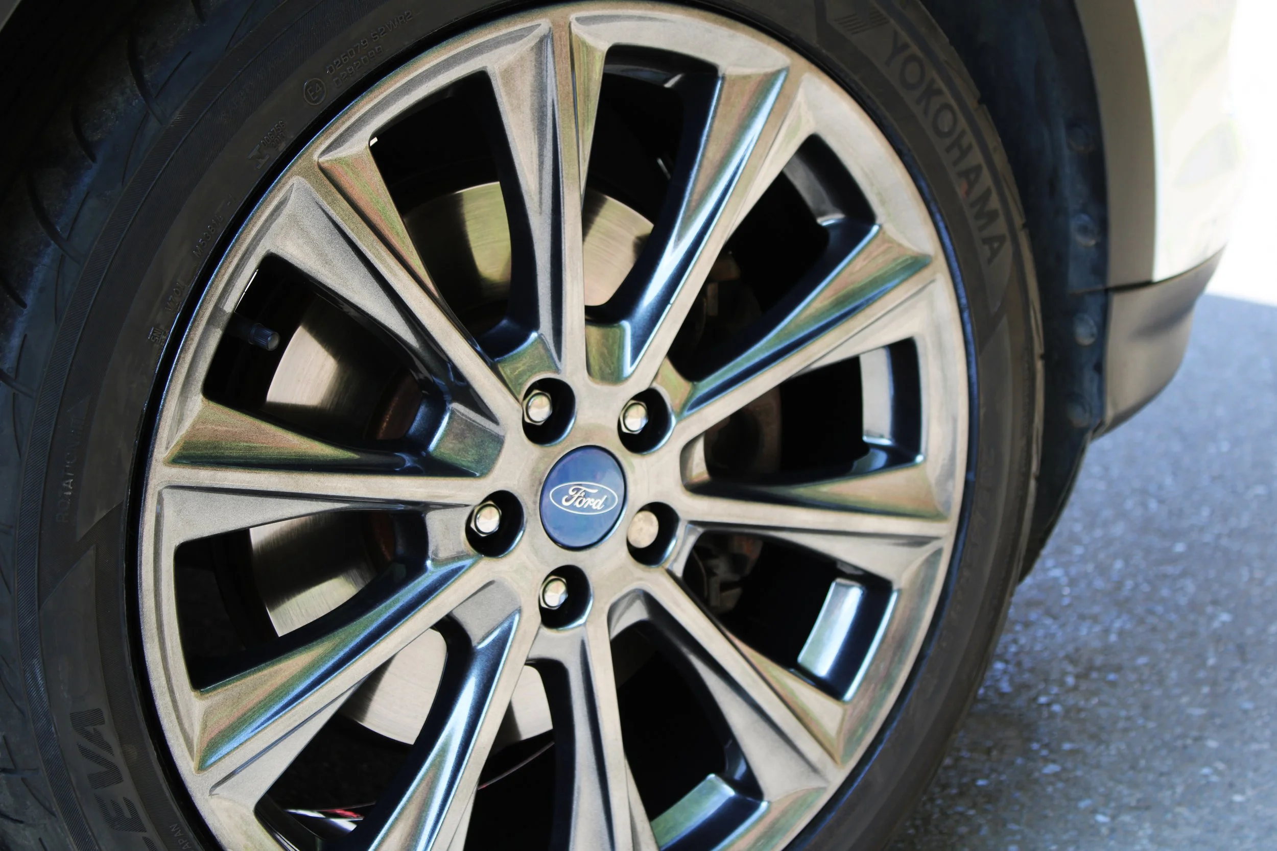 Close-up of a Ford vehicle's alloy wheel with a  multi-spoke design and a chrome finish.