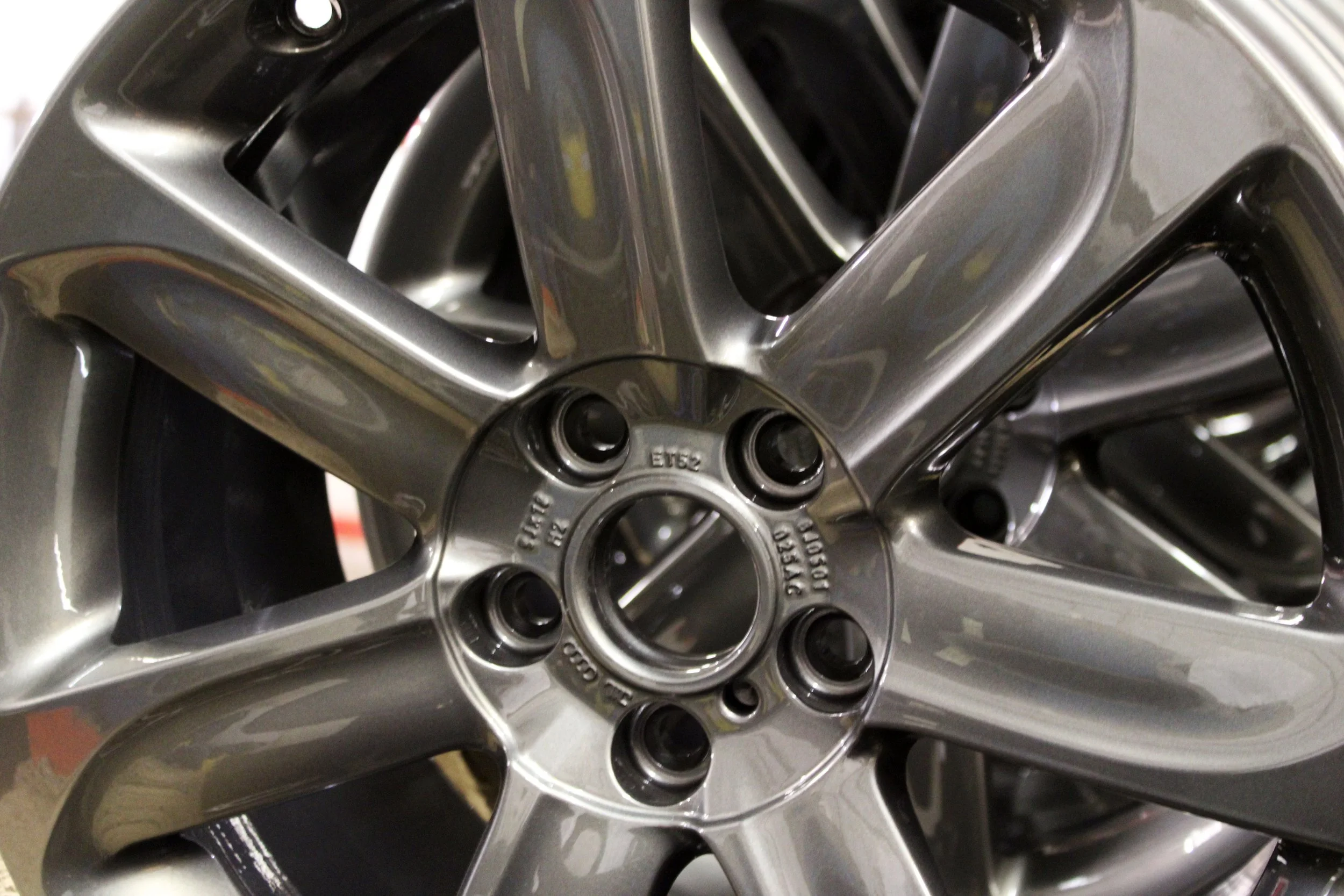 Close-up of a Anthracite Volkswagen car wheel with the brand logo in the center, showing part of alloy after a powder coat refurbishment.