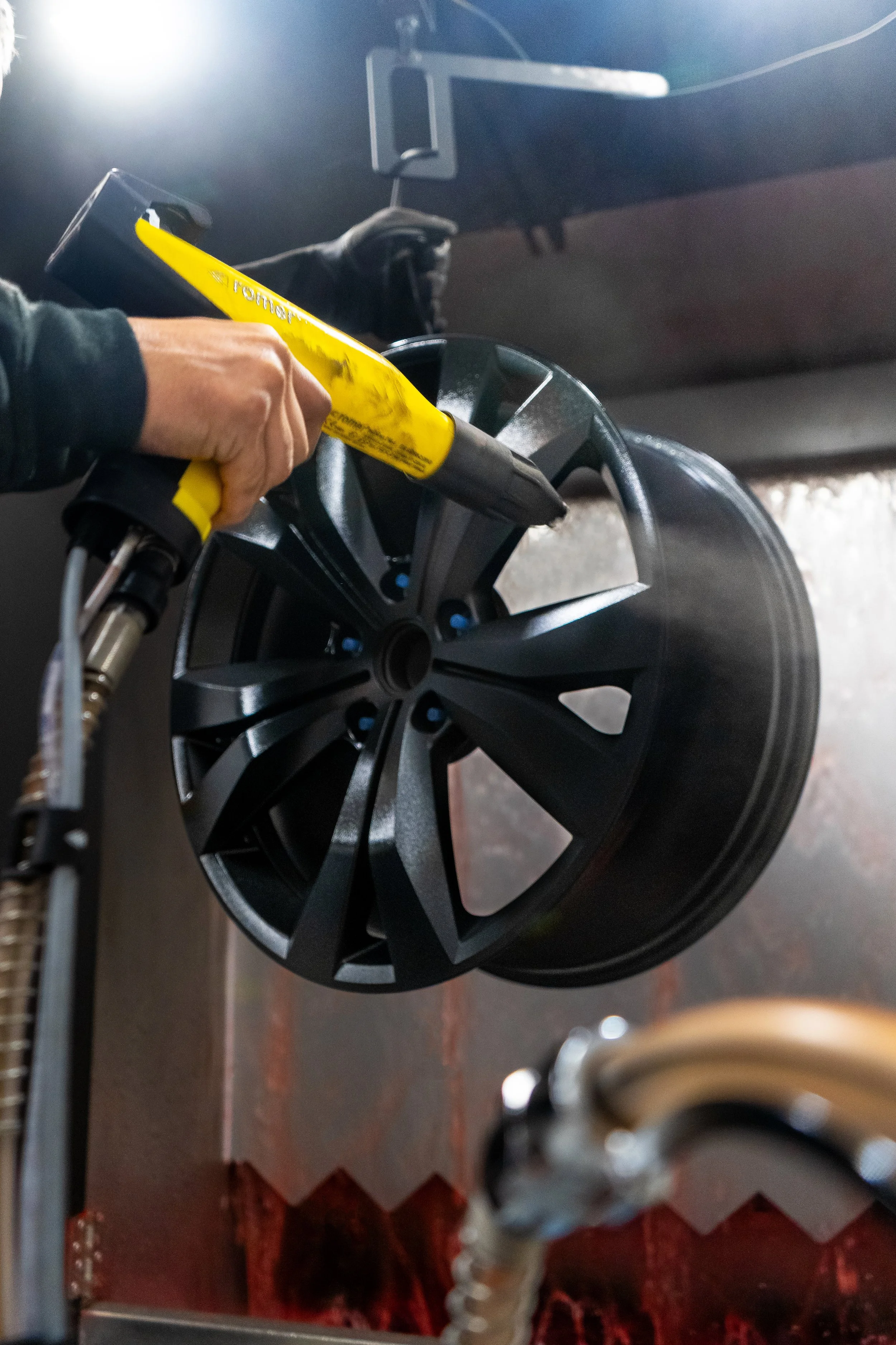 hand holding powder coat gun, spraying wheel