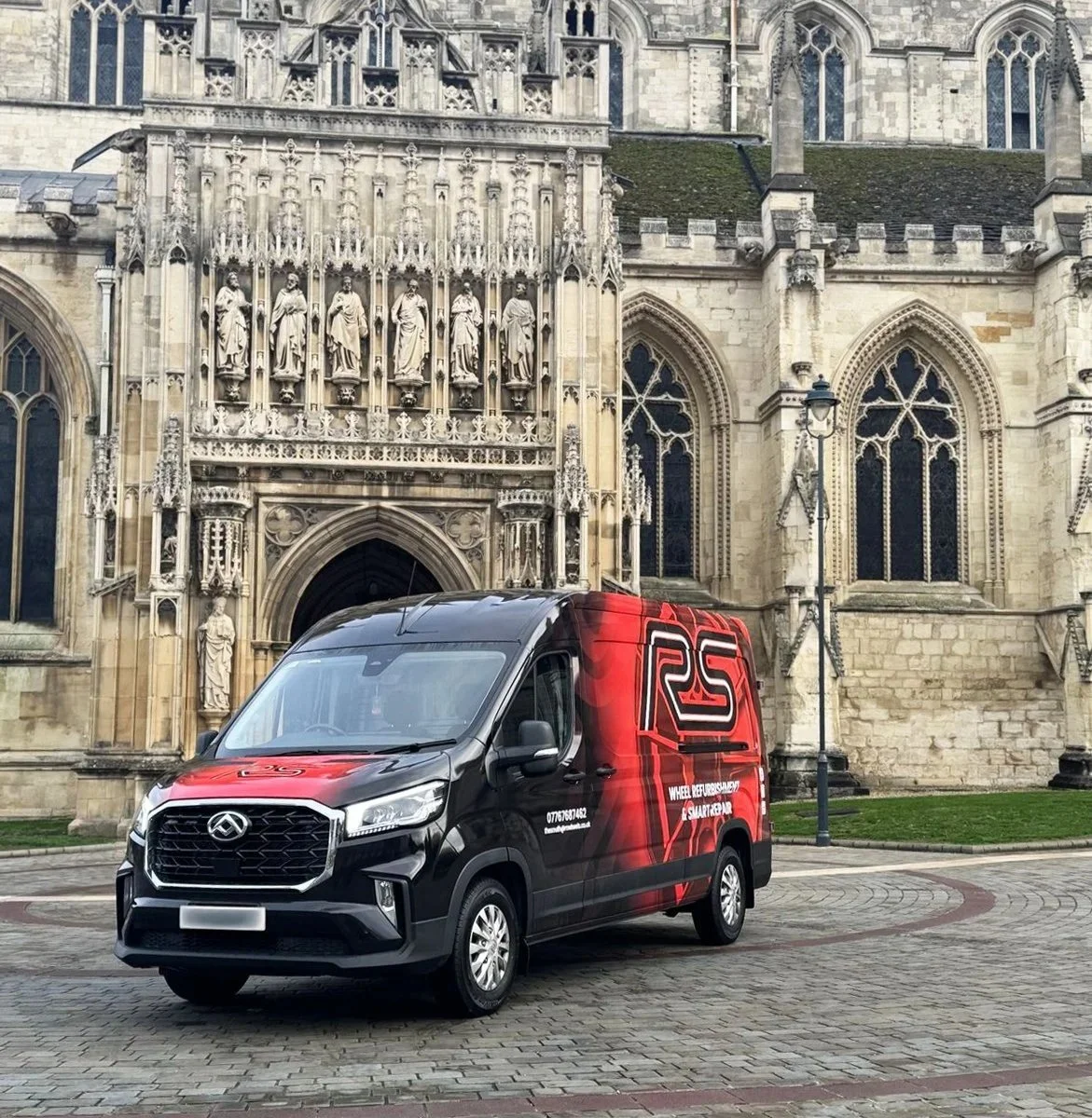 A black and red RS Wheels van parked in front of a cathedral.