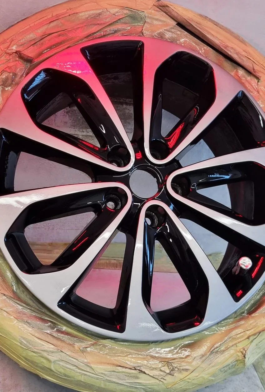 A black and diamond cut alloy wheel on a work bench being repaired. 