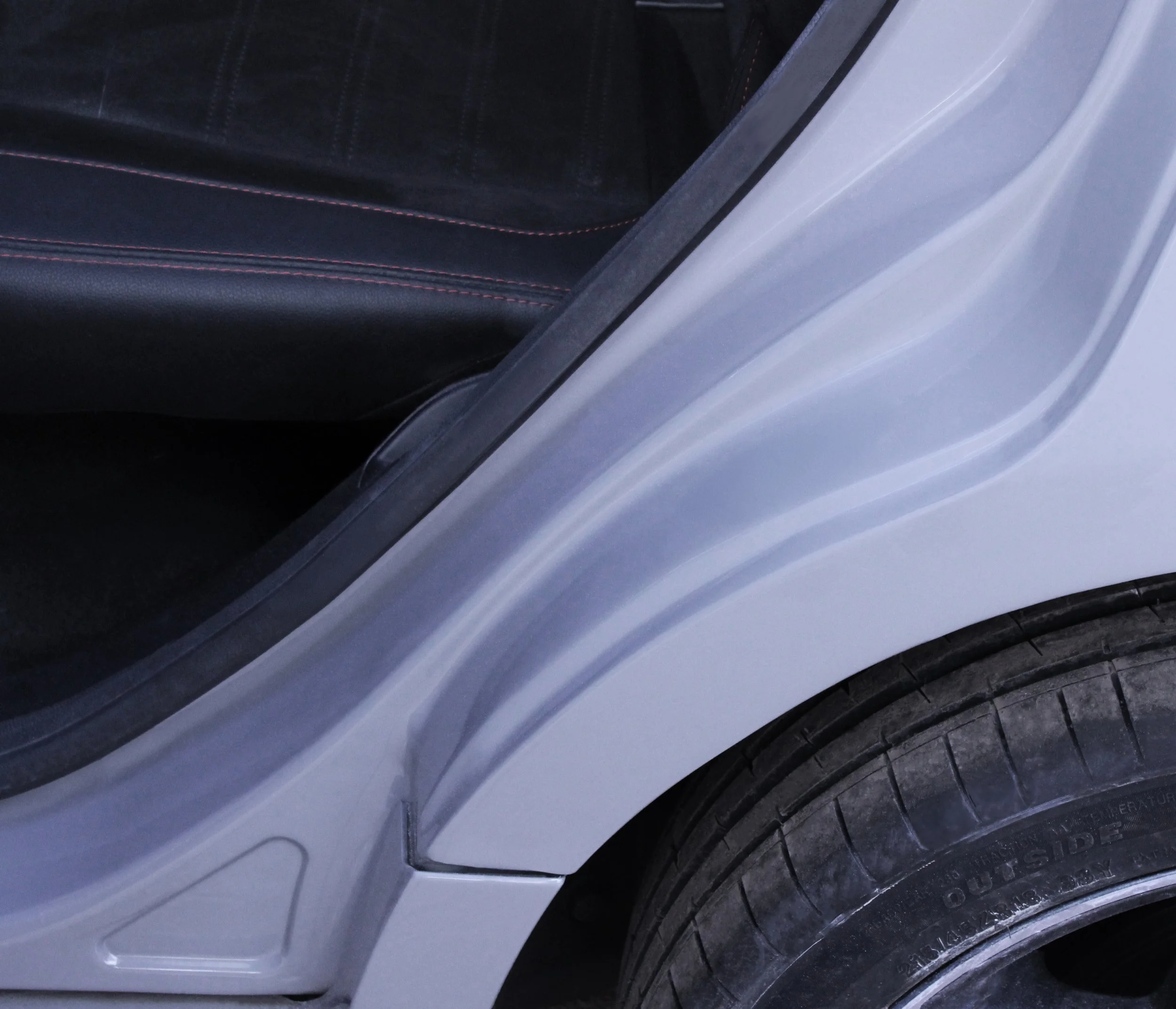 Close-up of the front right wheel and part of the door frame of a silver car, after the damage has been repaired in workshop.