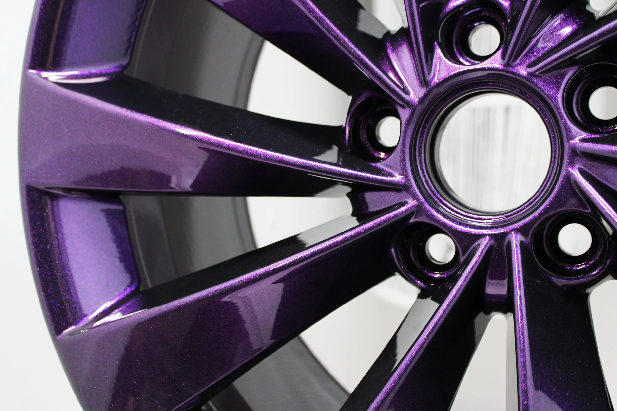Close-up photo of a purple metallic car alloy with a detailed spoke design.