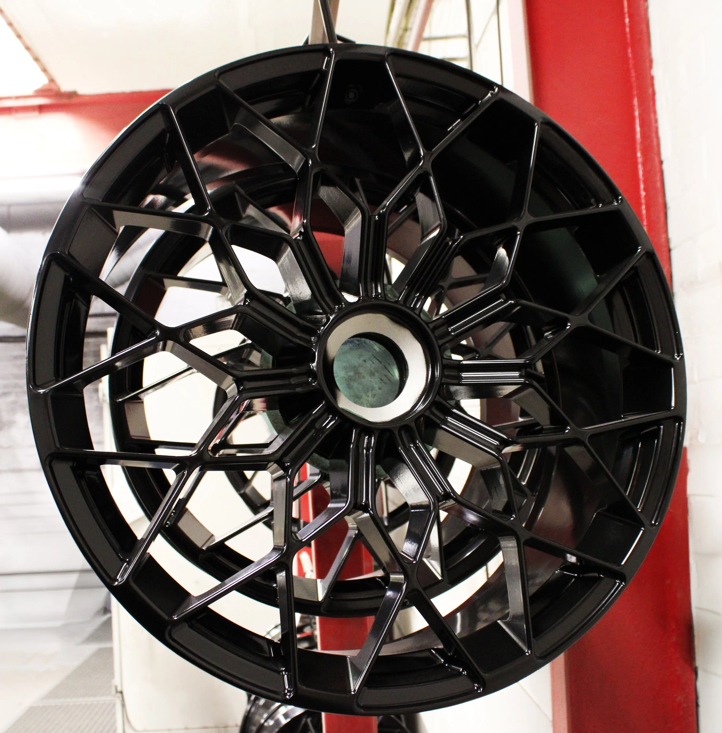 A Black Wheel Hung up on a drying rack after having a powder coat refurbishment