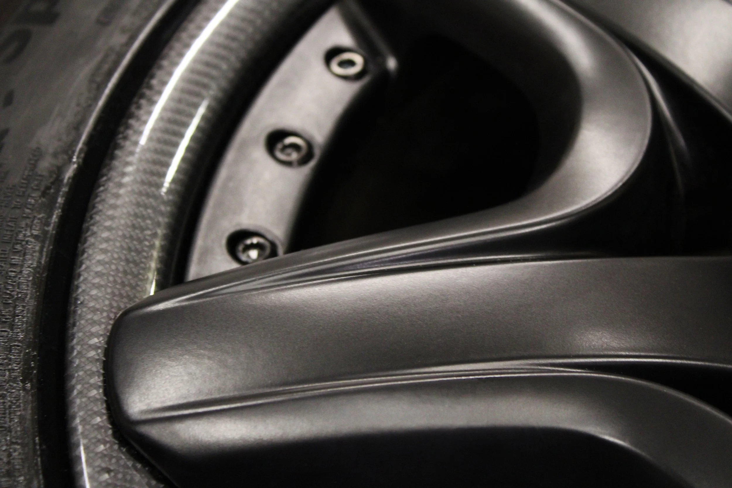 Close-up of a black carbon fiber and matte black split wheel.