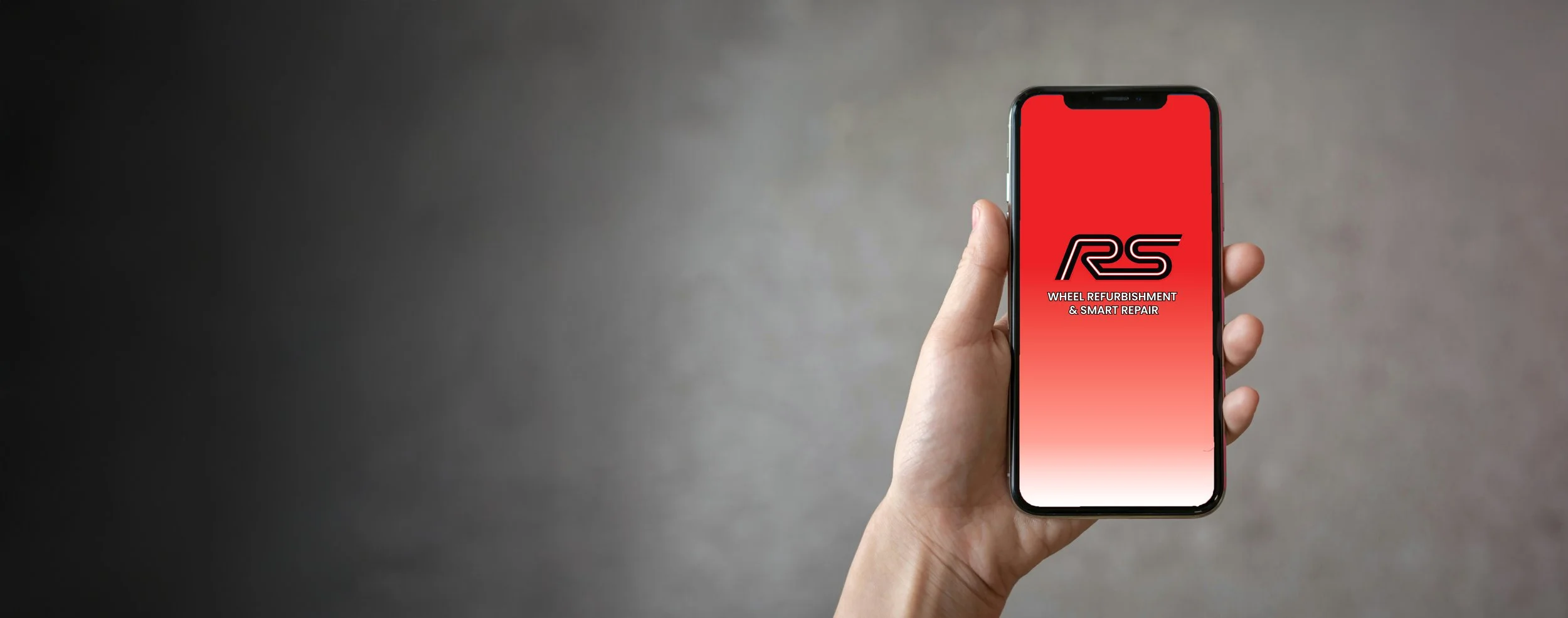 A person holding a smartphone with a red background on the screen, displaying a logo and text for wheel refurbishment and smart repair services.