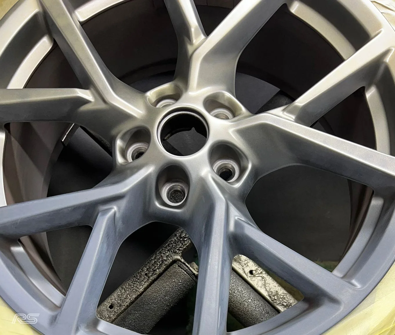 Close-up of a silver alloy in the process of being painted gold, placed on a work bench.
