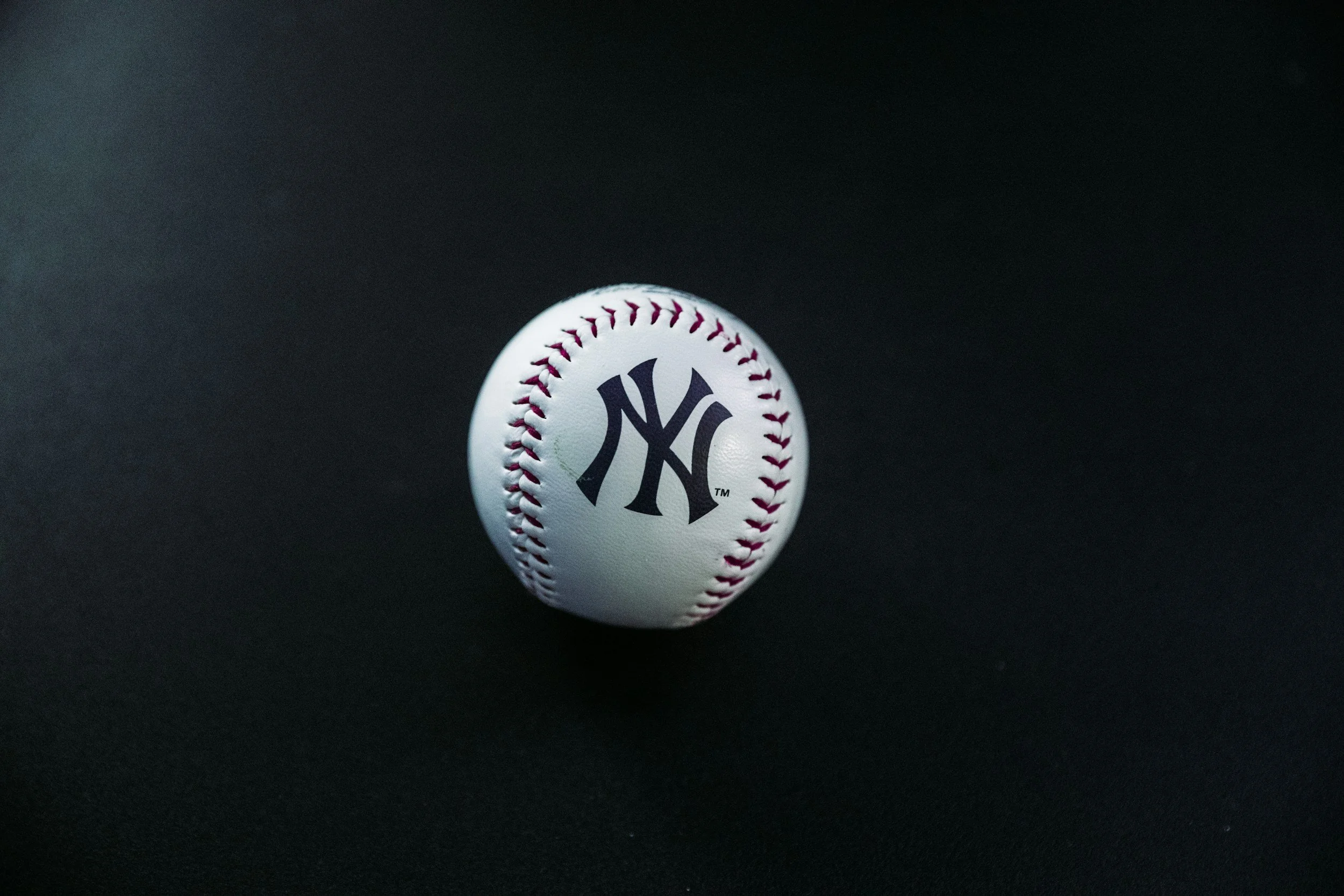 A baseball with the New York Yankees logo on it placed on a black background.