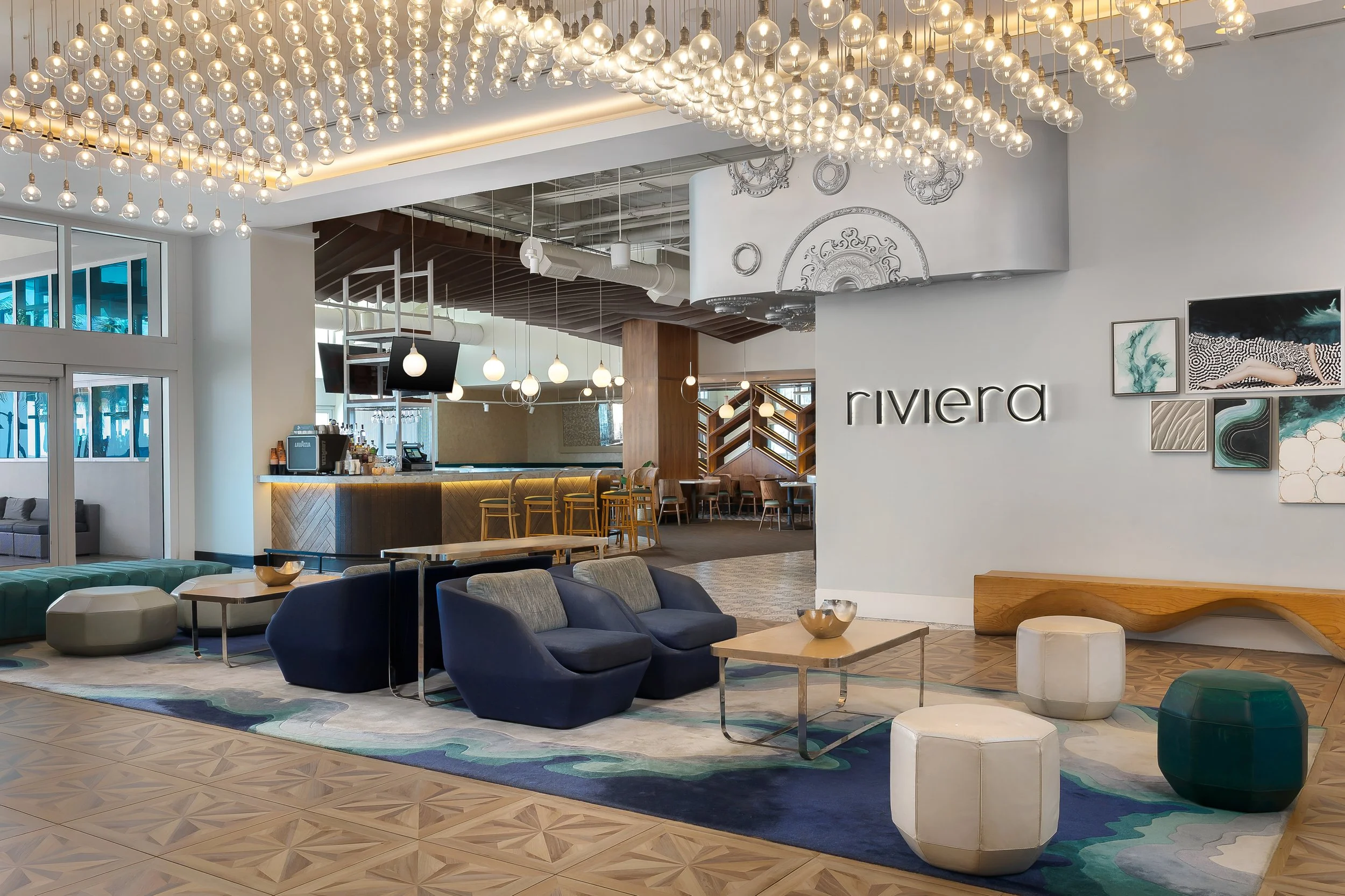 Interior of a modern hotel lobby with contemporary furniture, decorative art, and hanging globe lights.