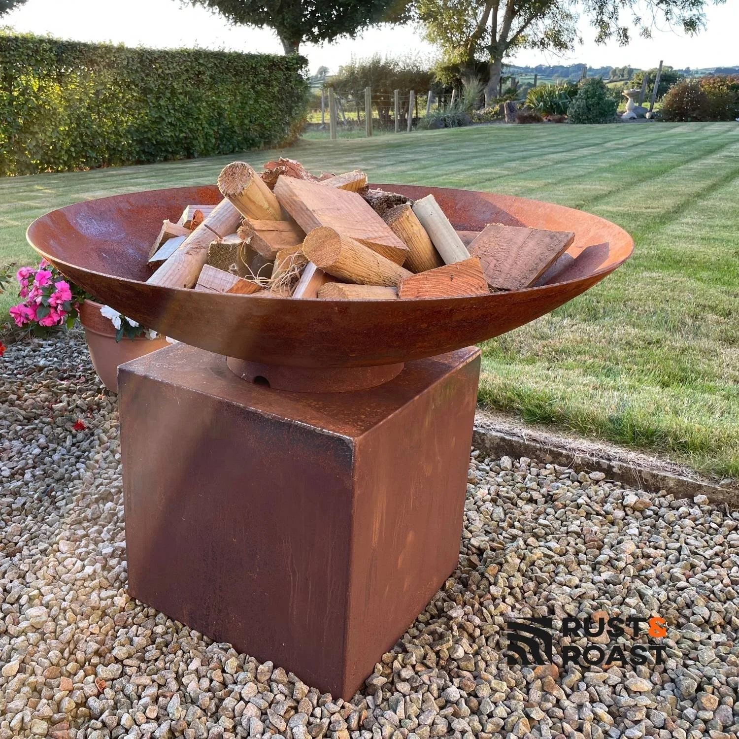 Modern steel fire bowl on a corten steel pedestal for outdoor gardens