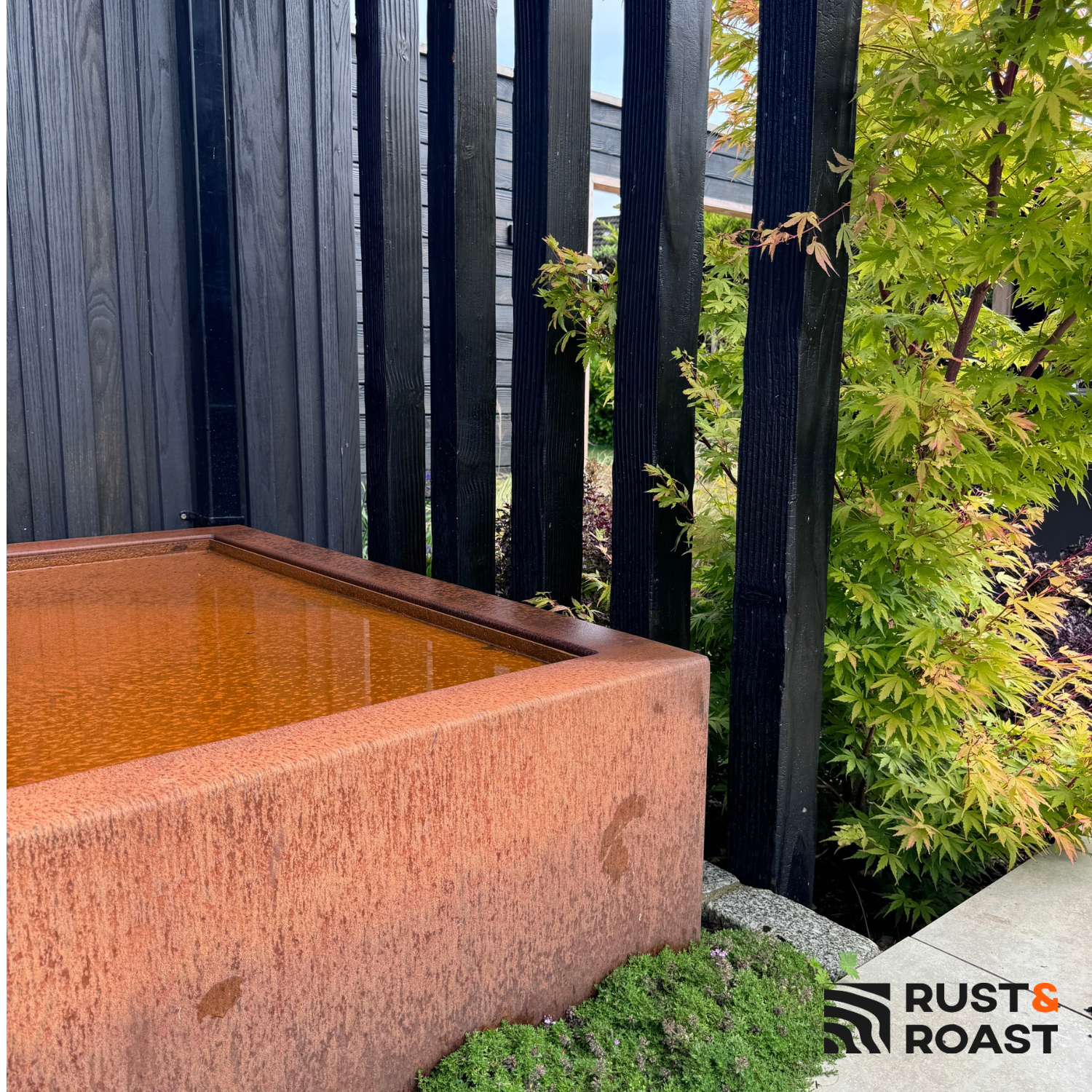 Weathering steel water feature with natural rust finish in landscaped garden