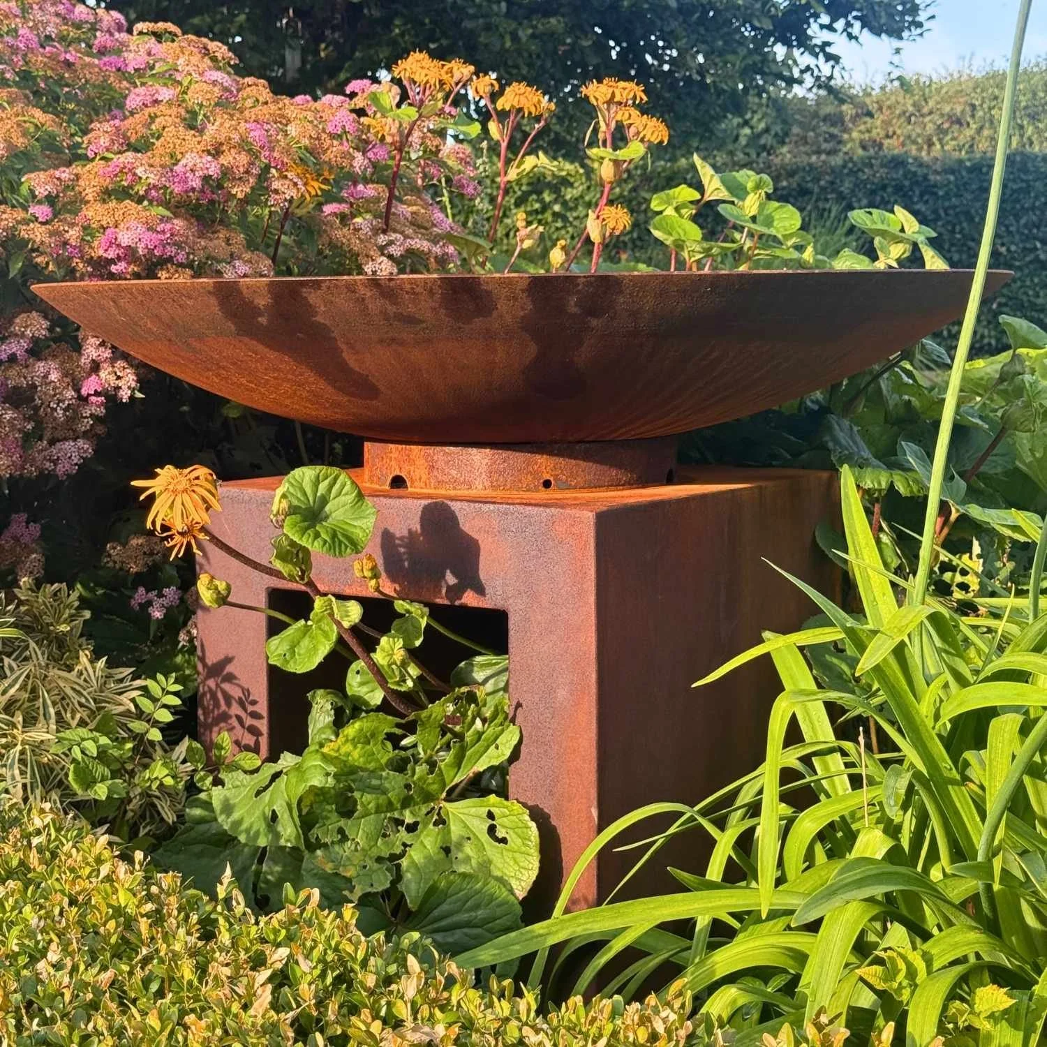 Modern corten steel water feature displaying the open U-shaped pedestal in a landscaped setting.