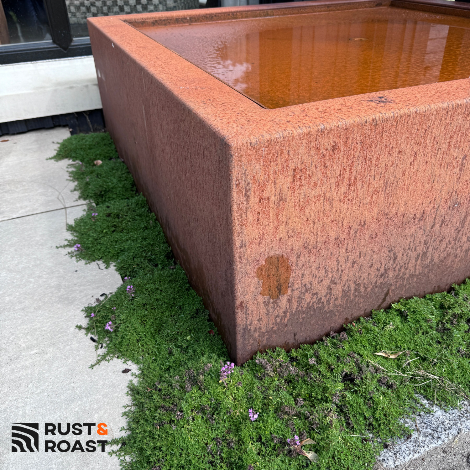 Close-up of corten steel water table showing natural weathered patina