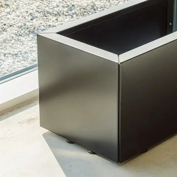 Black metal planter box on concrete floor next to a window