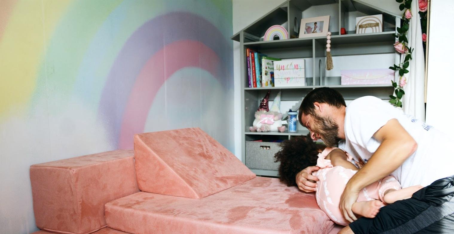 Dad and toddler playing on a pink play couch