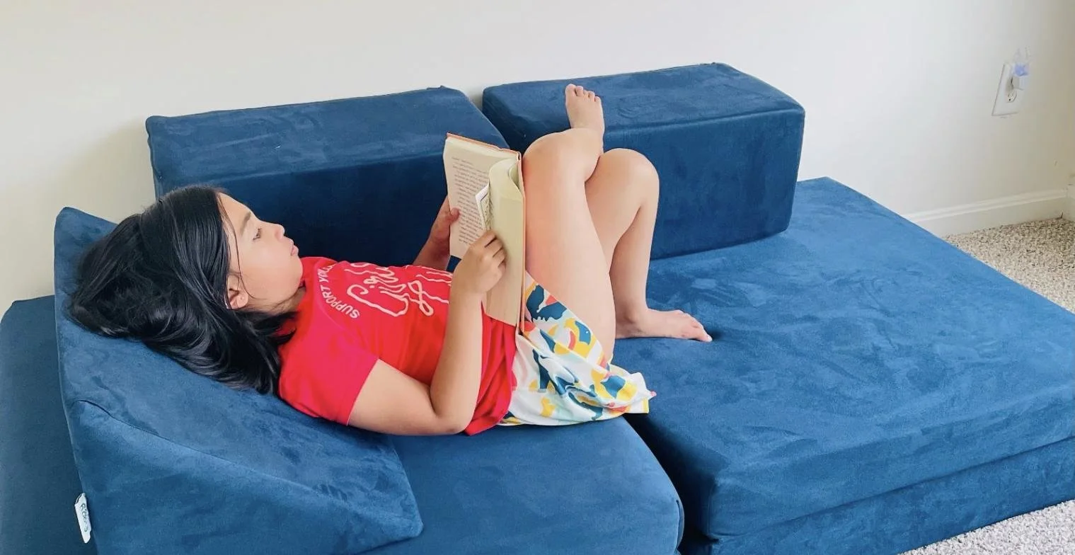 Child reading on a freshly washed navy play couch