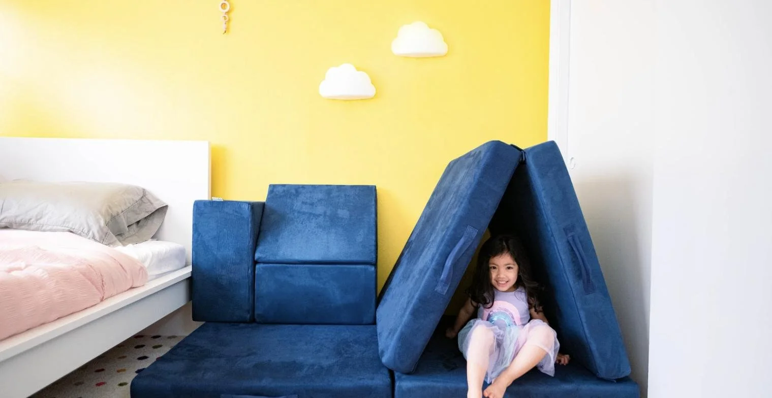Child inside a play couch fort in a bedroom