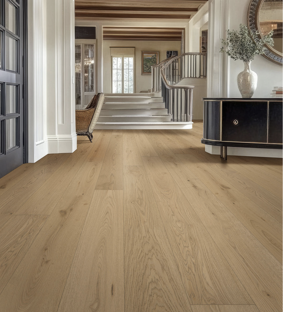 Living room with natural wood flooring, staircase, black sideboard with a large vase and greenery, and artwork on the walls.