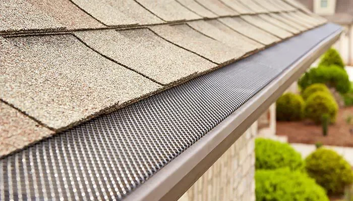 Close-up of a house roof with asphalt shingles and gutter guard.