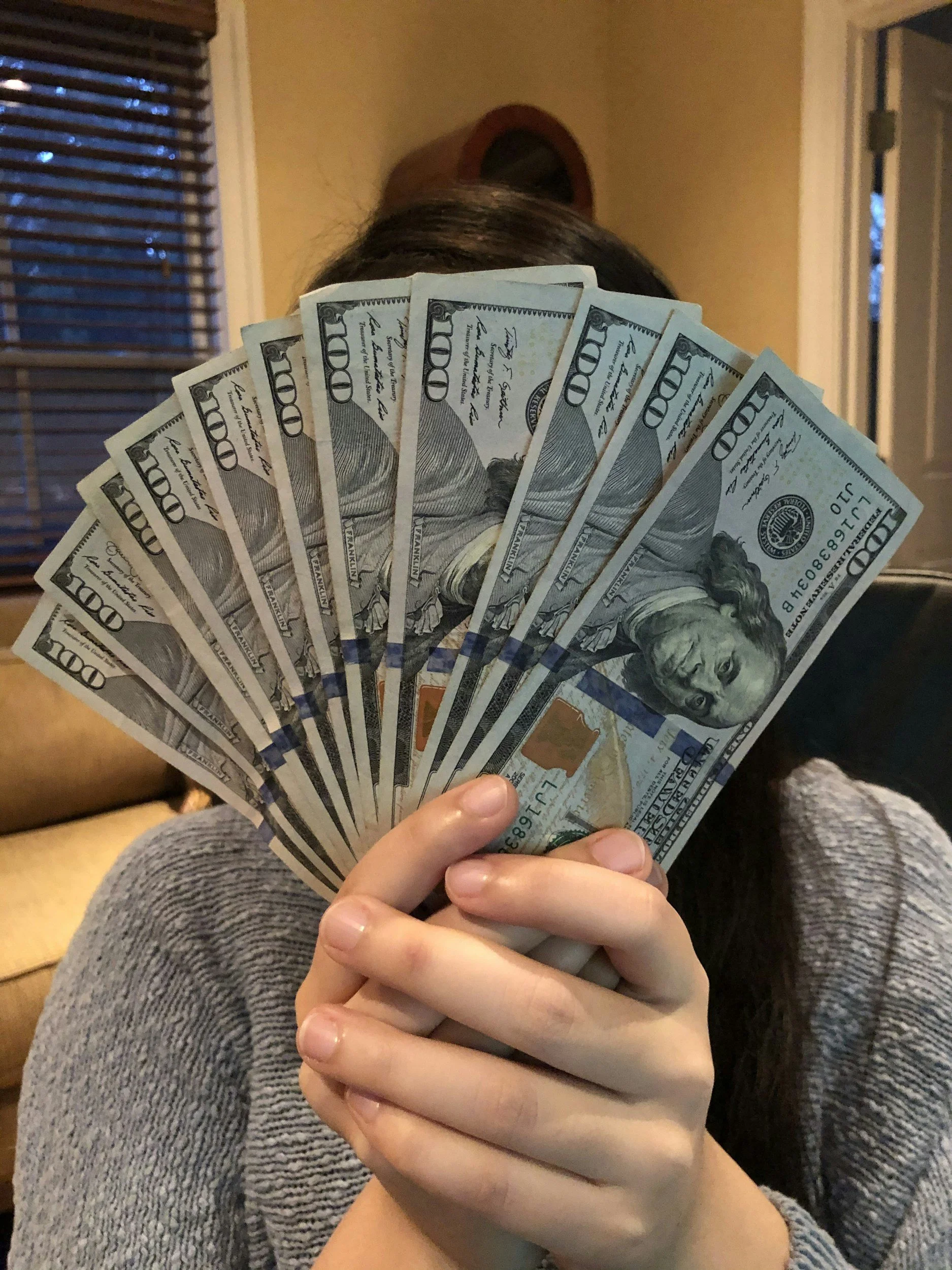 a person hiding behind an array of $100 dollar bills, symbolizing the faceless buyers who are looking to buy homes ahead of the implementation of OH SB 155