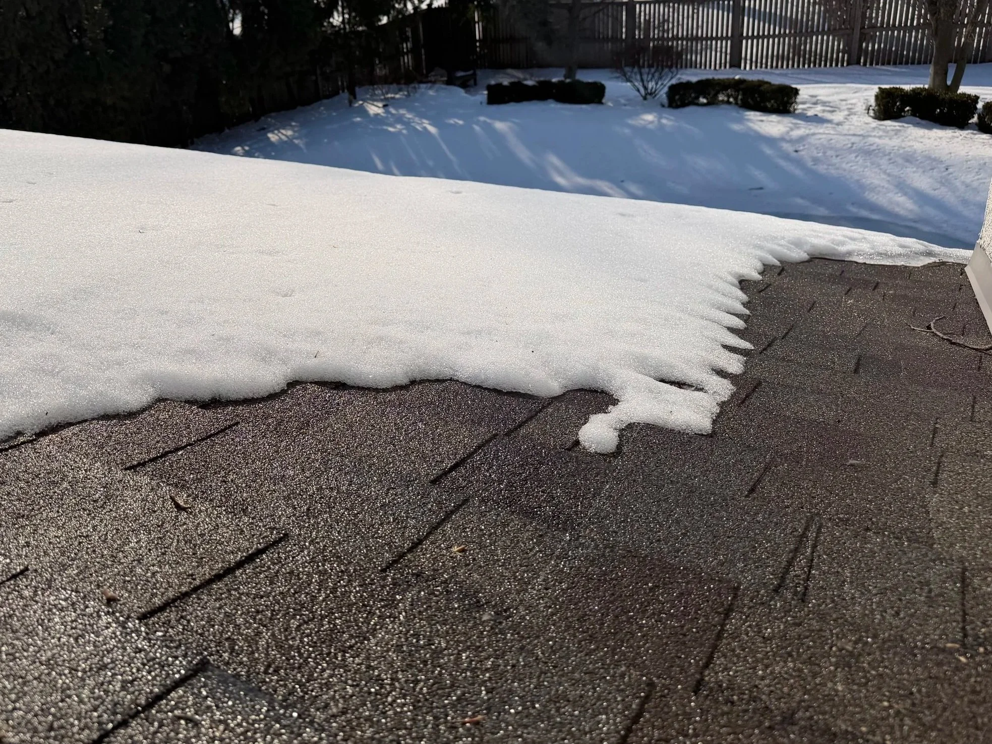 Snow melting along a roof edge and flowing into the gutter during a winter thaw.