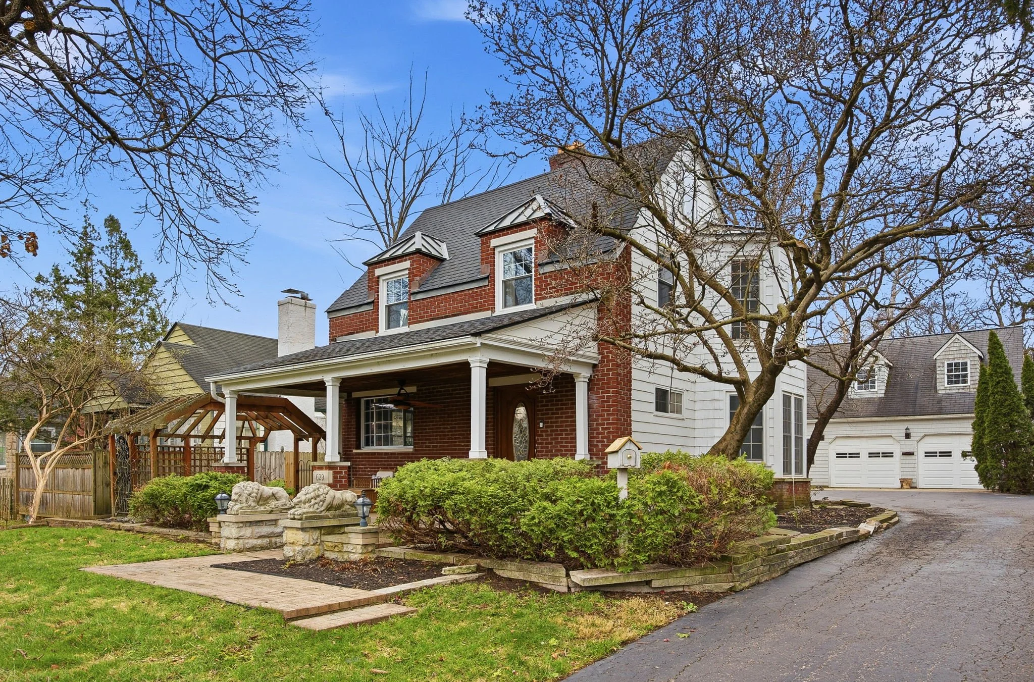 A charming brick home, featuring a pair of stone lions to welcome guests to the inviting front porch.