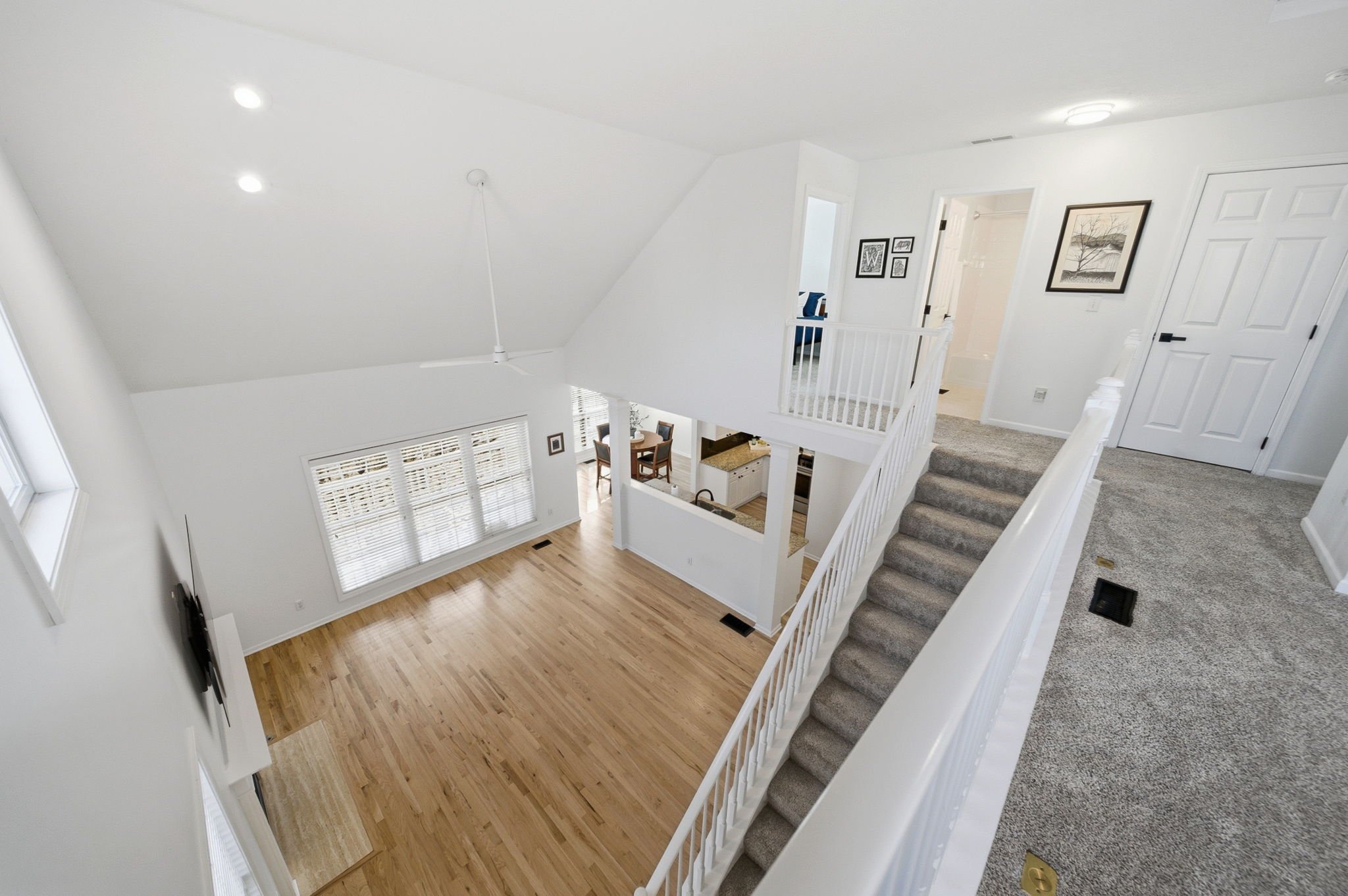 This stunning two-story great room features walls of windows, gleaming hardwood floors, and natural light that fills the space from morning to evening.