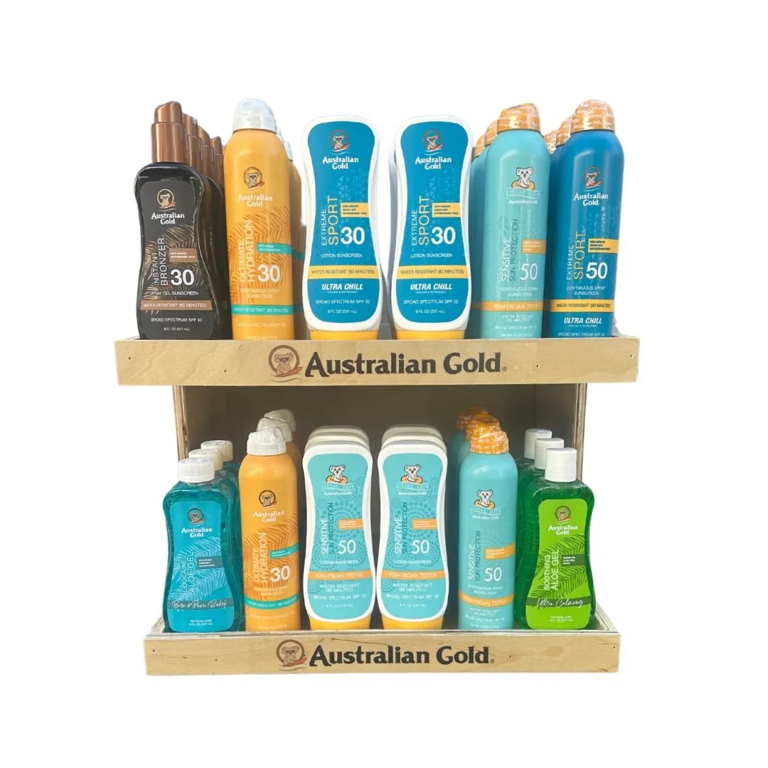 Display of Australian Gold sunscreen and after-sun products on a two-tier wooden shelving unit.