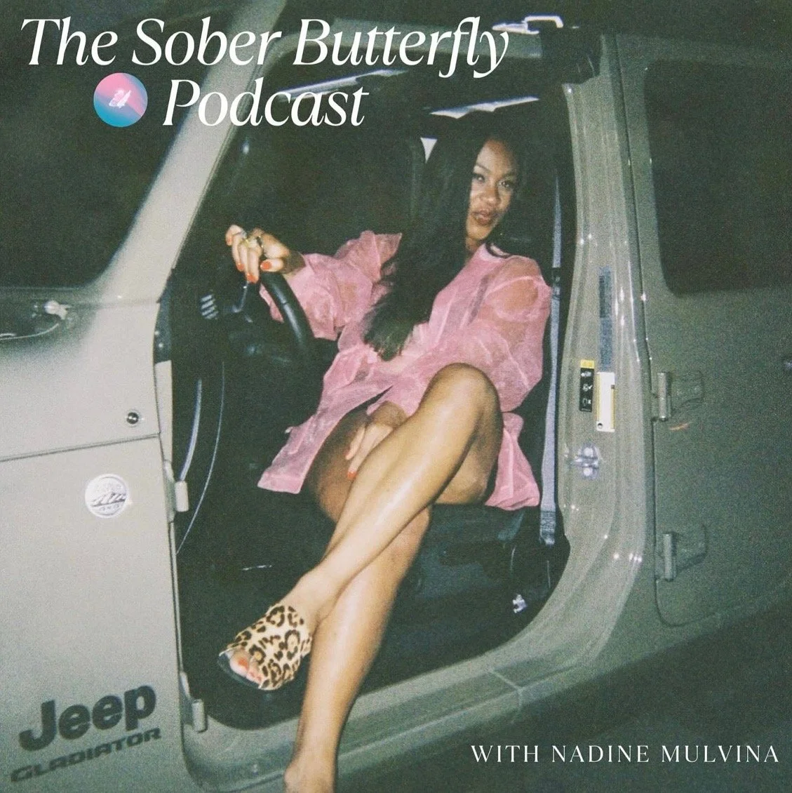 woman is getting out of her open door jeep. She is wearing cheetah shoes and a pink blazer