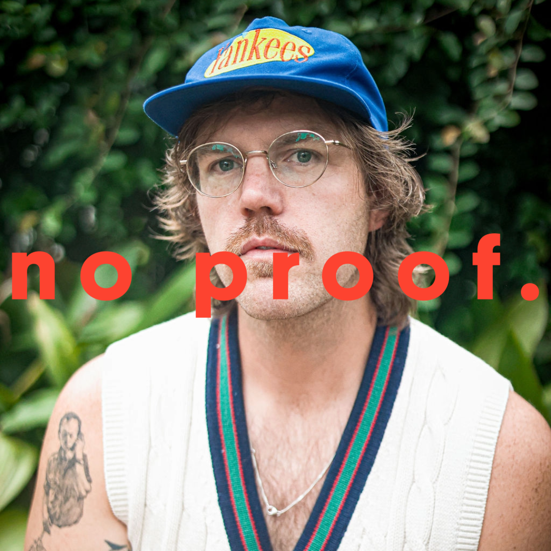 man with v neck vest, tattoo on left sleeve, wearing a blue yankees hat and glasses and has a solemn look on his face. THe words "no proof." are on top of the image