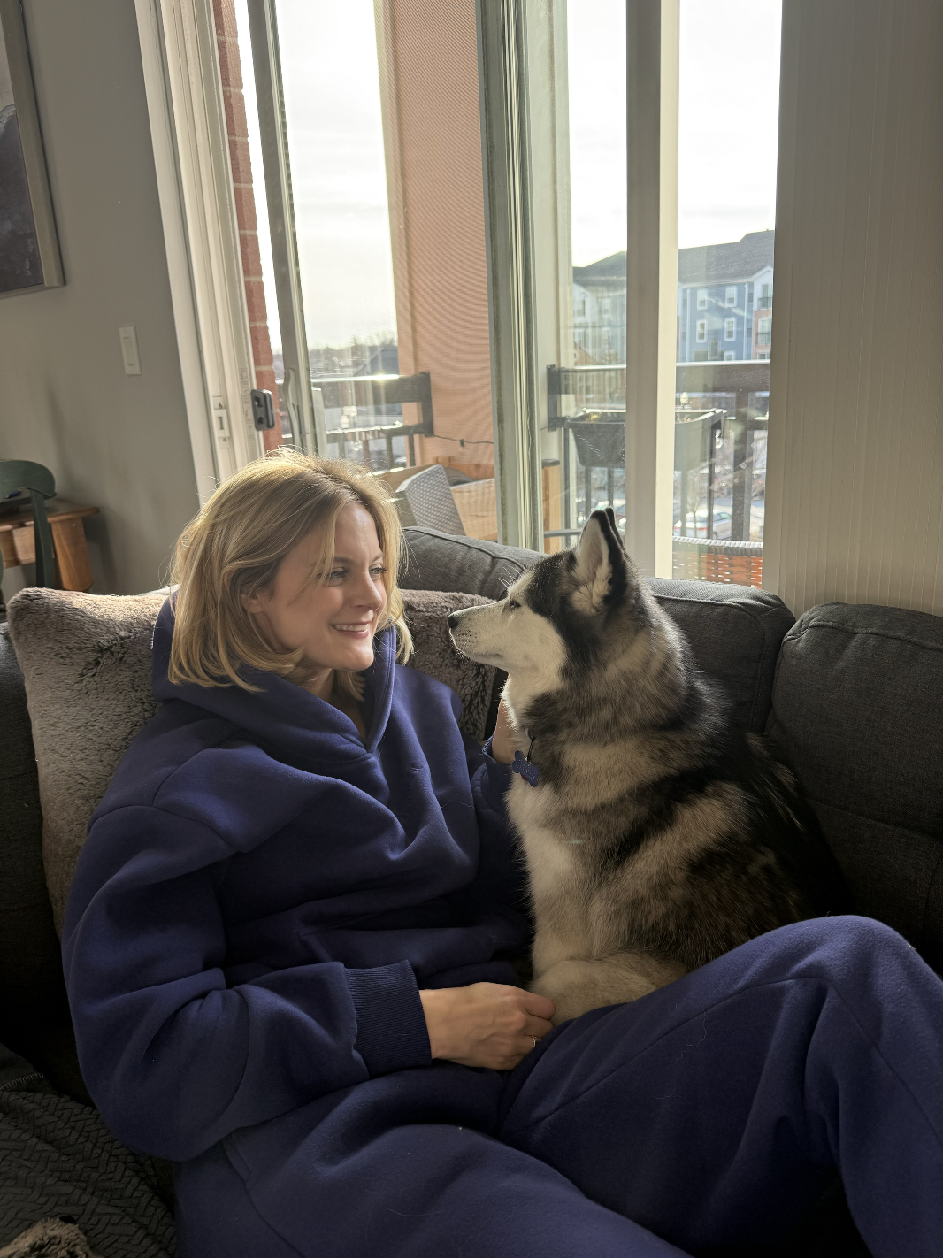 blonde woman sits on couch with dog