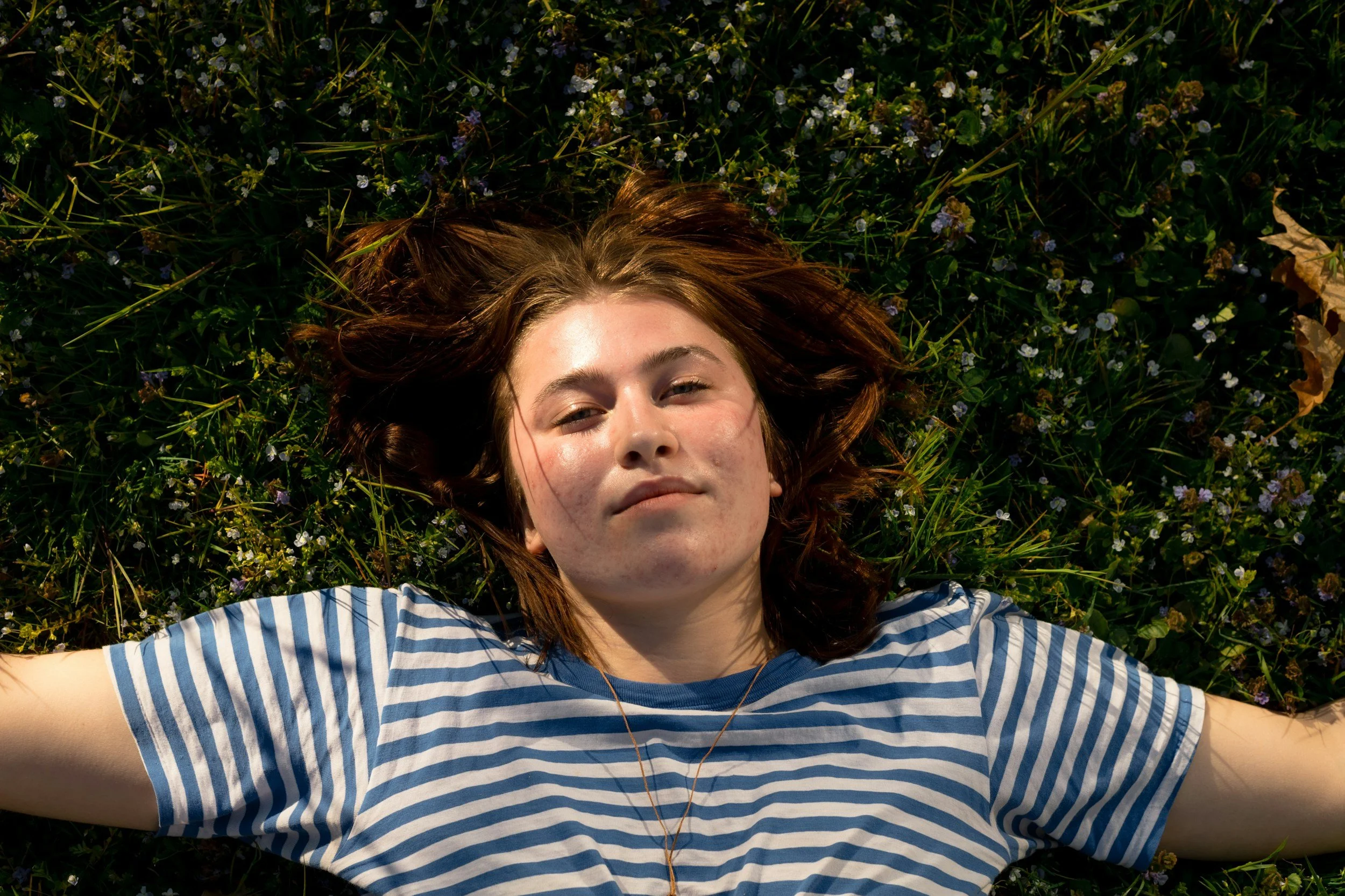 A body conscious patient lying down on grasses and smiling