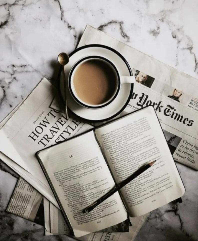 Picture of a NYC NYT magazine with a cup of coffee and a journal sitting on top
