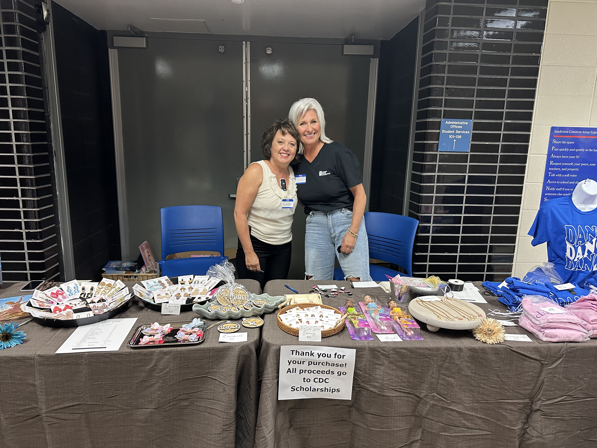 Two adults leaning in towards each other working the merchandise table