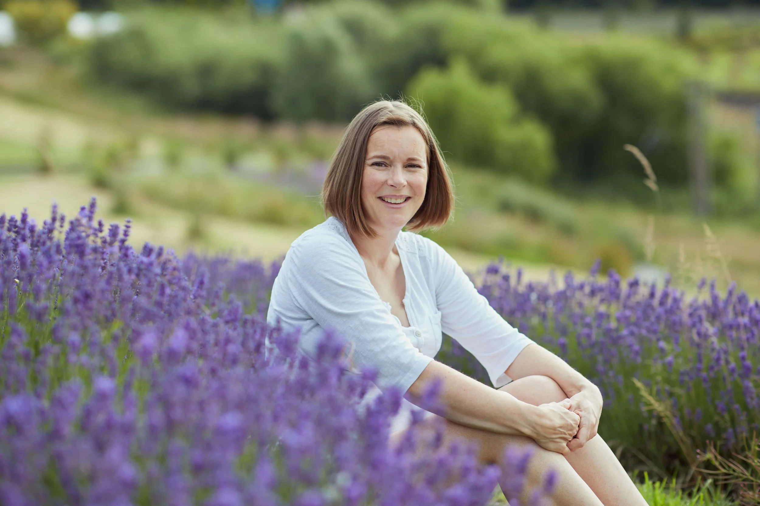 Jess from Jess Evans yoga sits amongst the lavender smiling, after her yoga class at Yorkshire Lavender