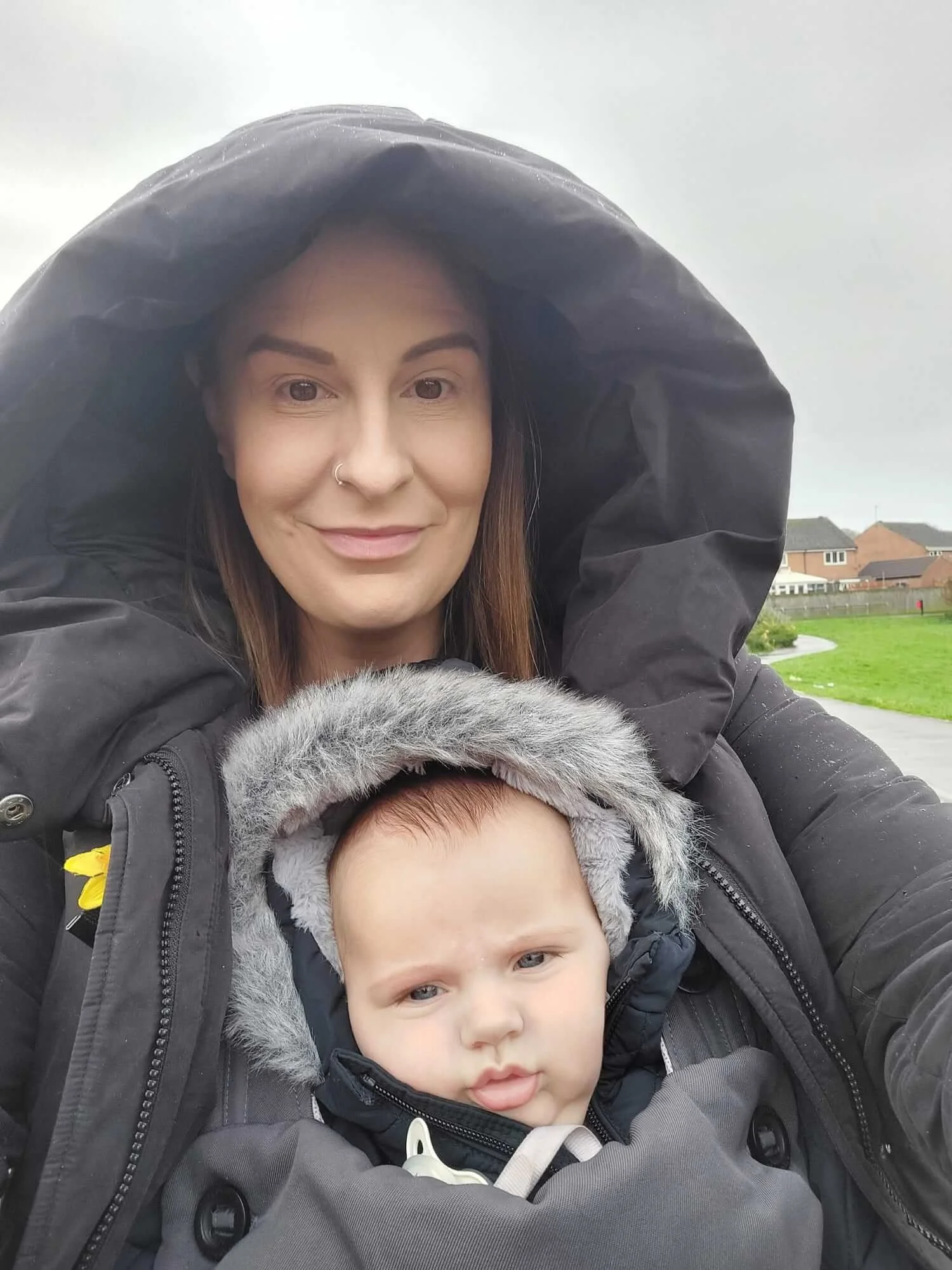 A mum carries her baby in a baby carrier as she walks to their baby massage class in Malton