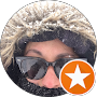 Persona con gafas y gorro de piel, sonriendo y de fondo con nieve.