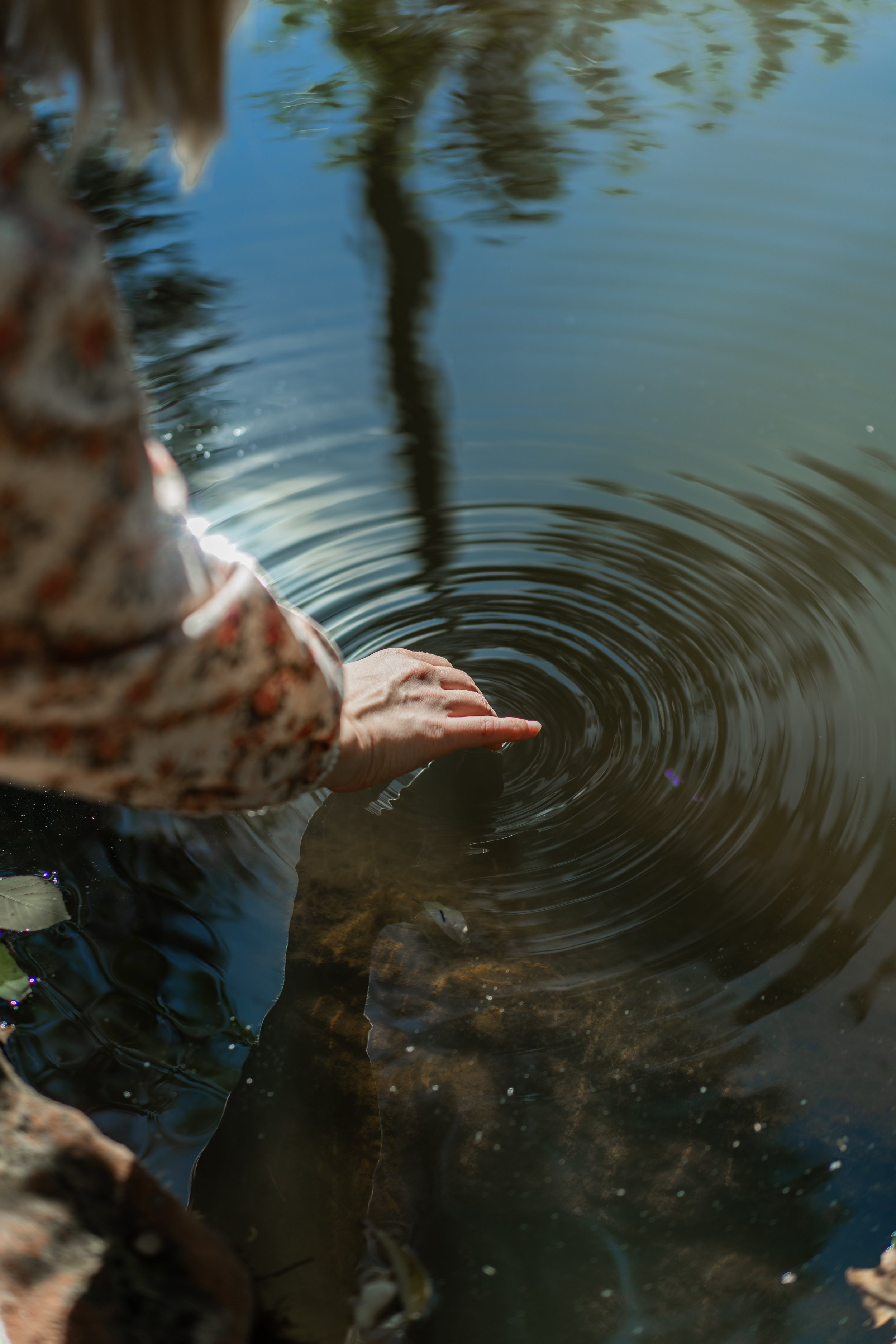 Person reaching into the water to catch a fish.