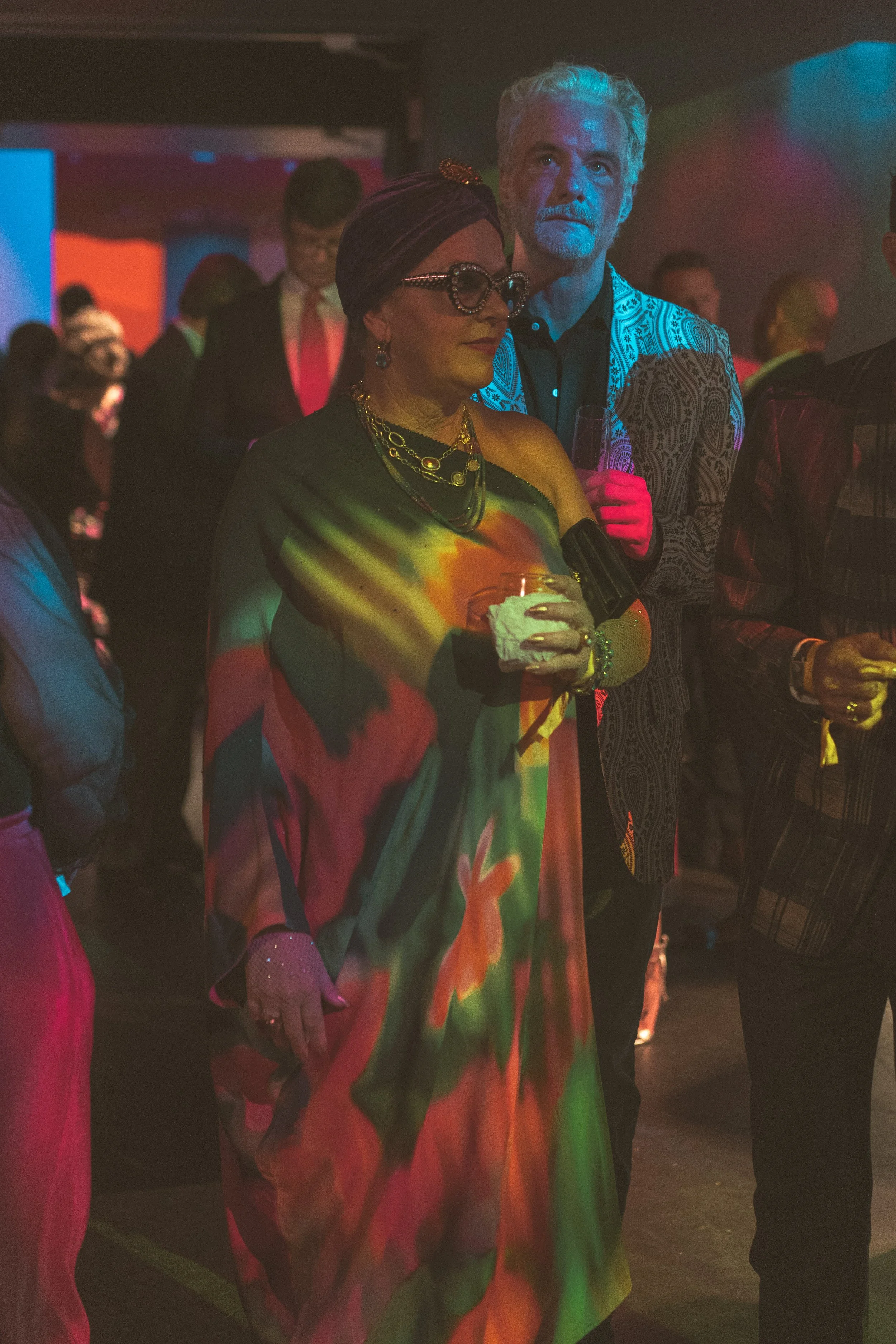 People dancing at a party with colorful lighting.
