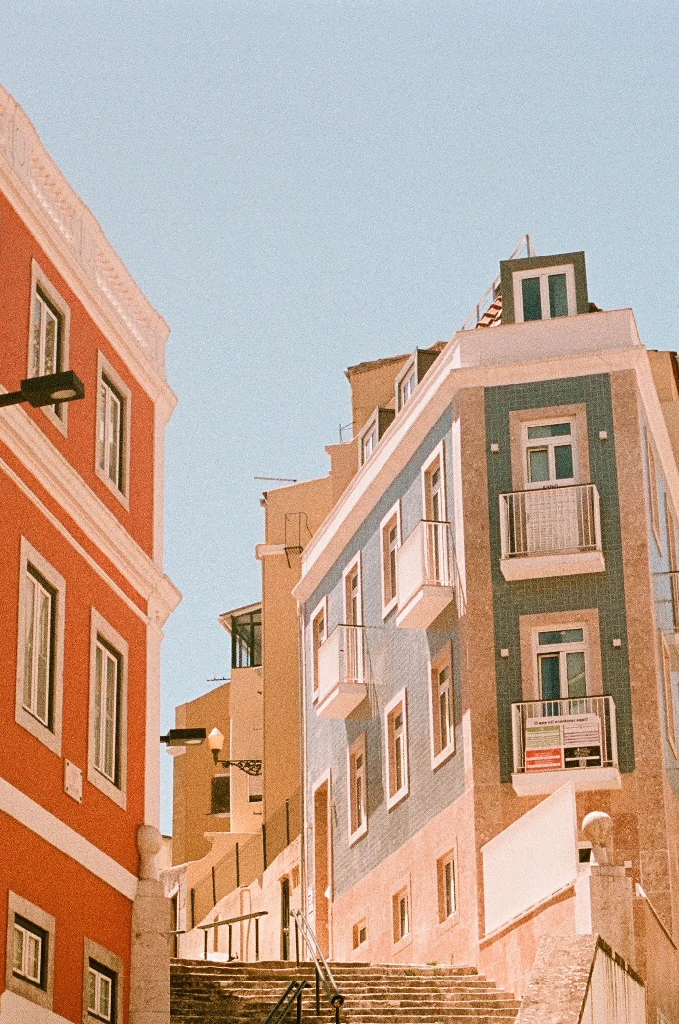 Colorful buildings on a steep street with stairs, under a clear blue sky.