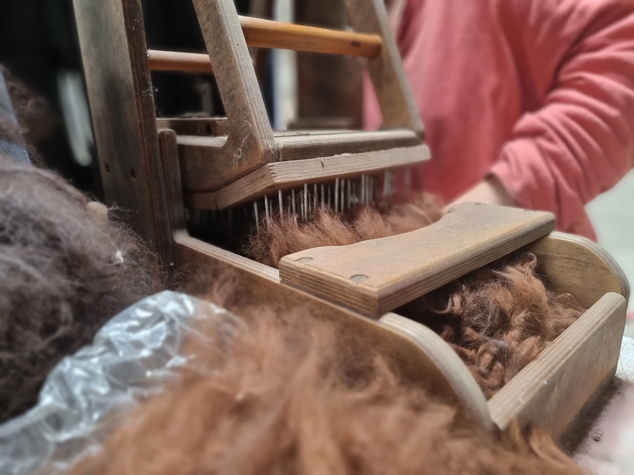 Close-up of a wooden loom with yarn, surrounded by wool from our alpacas at Monte Frio Alpacas.