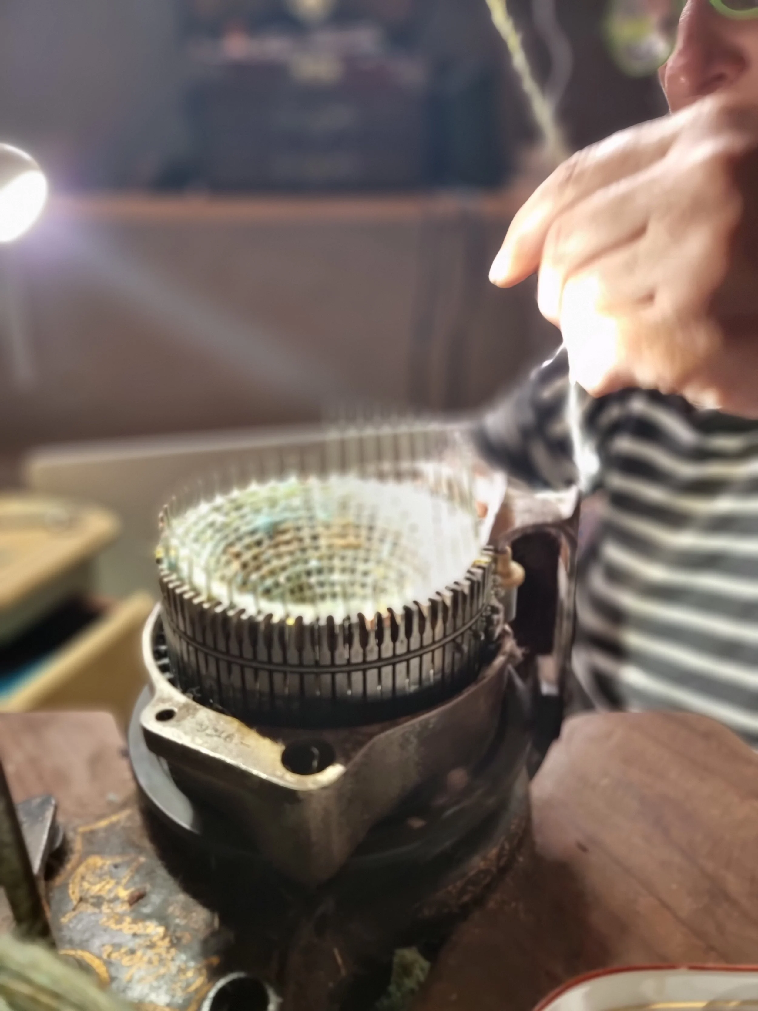 A person wearing a striped shirt is working on a Portuguese spindle workshop at Monte Frio Alpacas.