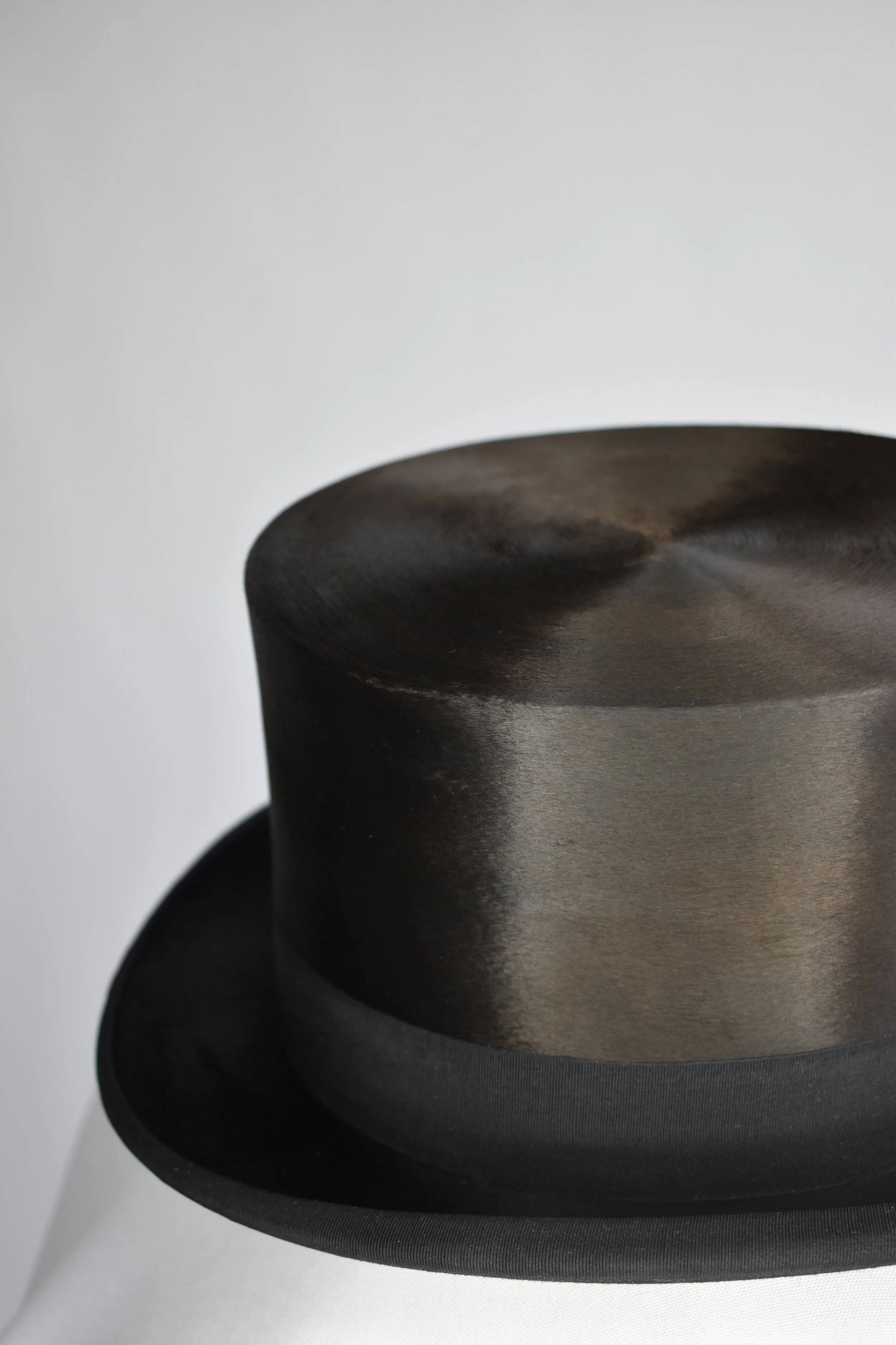 Close-up of a black metal object with a curved, dark, smooth surface against a light gray background.