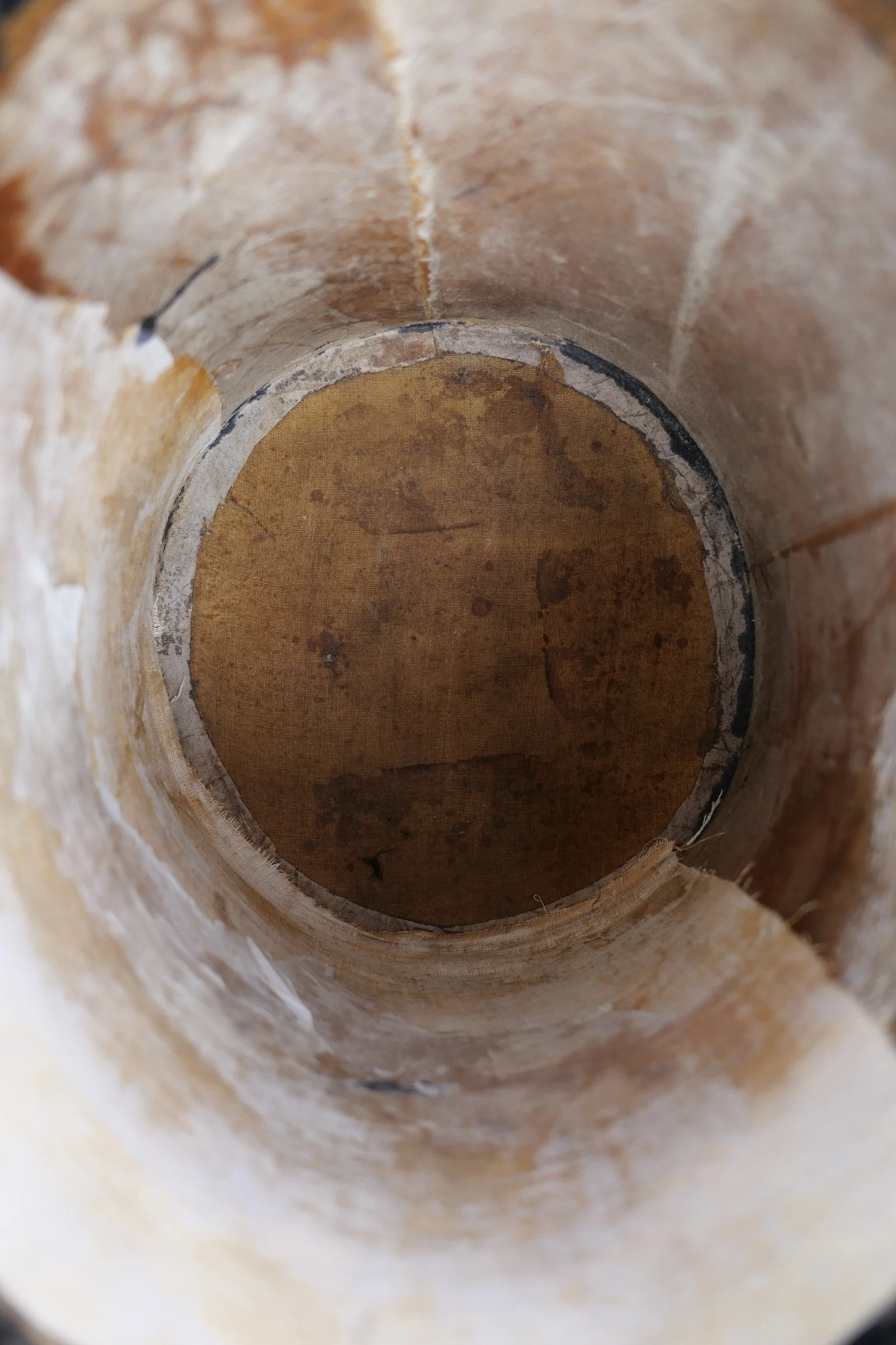 Looking inside a large, empty, rust-colored pipe or tunnel with rough, stained walls and a textured floor.