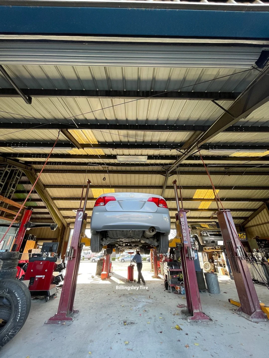 Keeping Coalinga cars running, one oil change at a time. Old-school work means taking the time to do it right.
A routine oil change in progress. A car is raised on a lift while a technician works below, with tools and equipment nearby during a normal