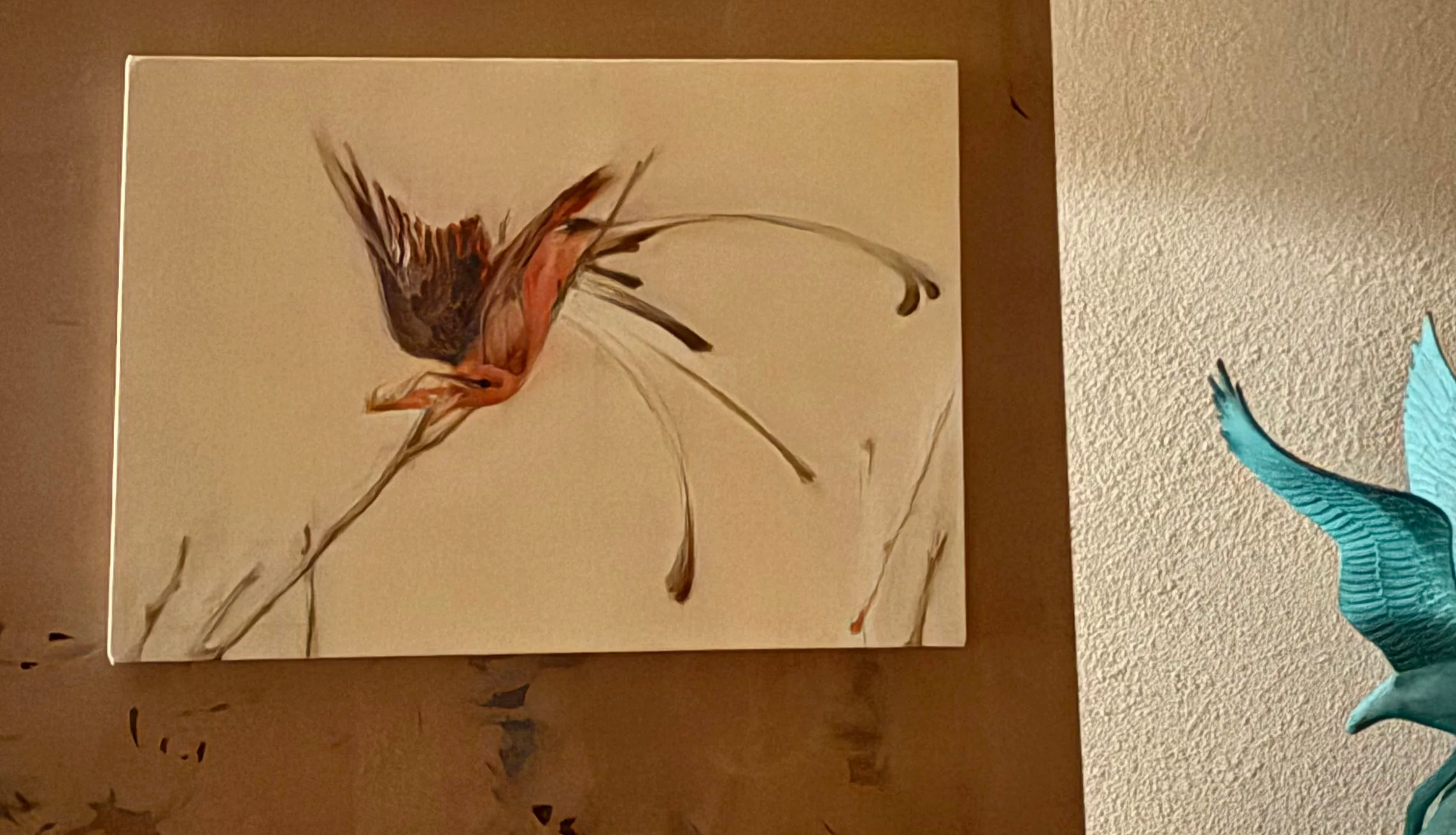 Painting of a bird with colorful feathers perched on a branch, with a blue dragonfly decoration beside it.