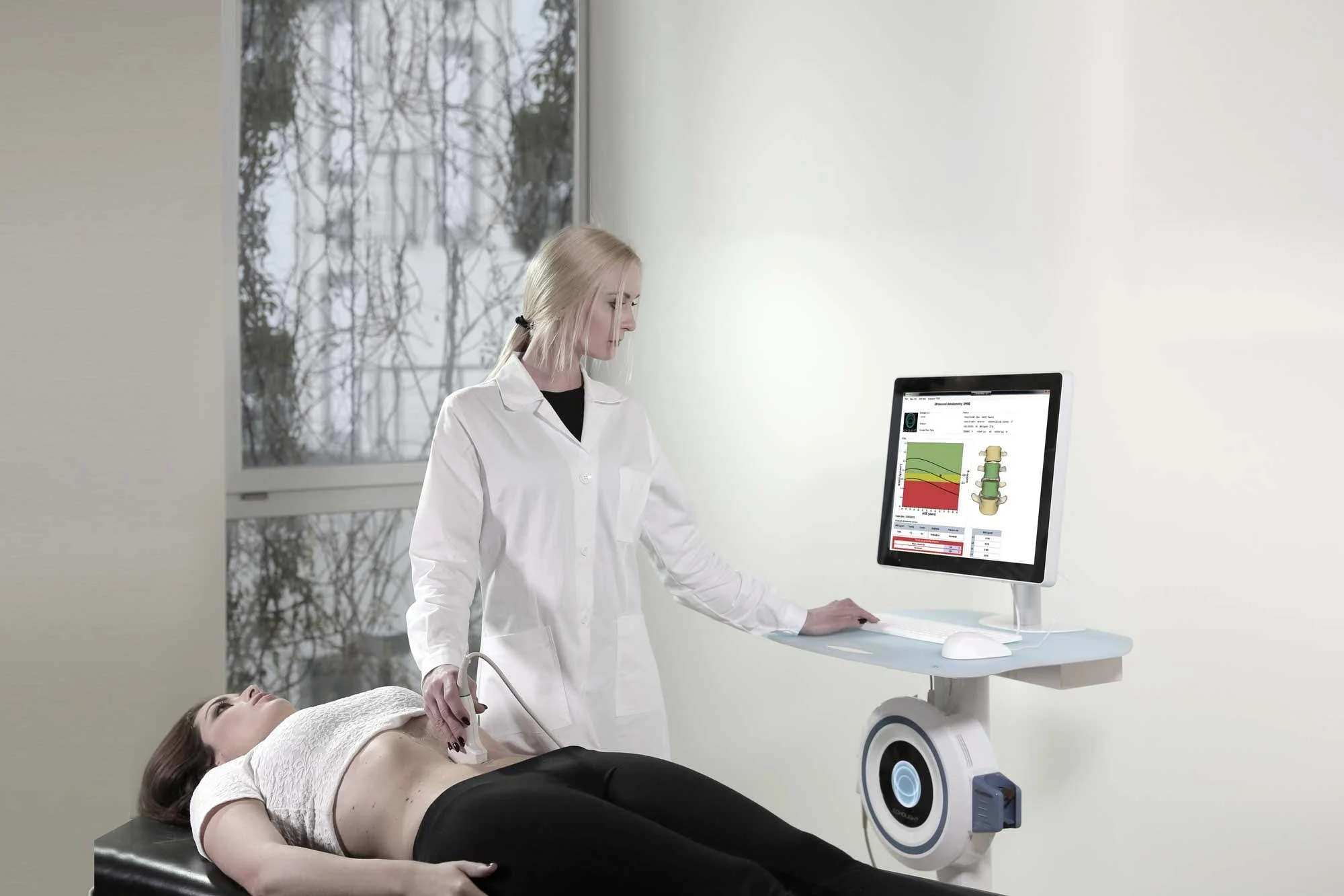 Medical technician performs REMS scan on female patient while reviewing report on a computer monitor.
