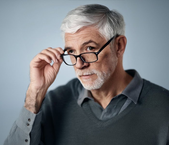 A senior man lifting up her eyeglasses