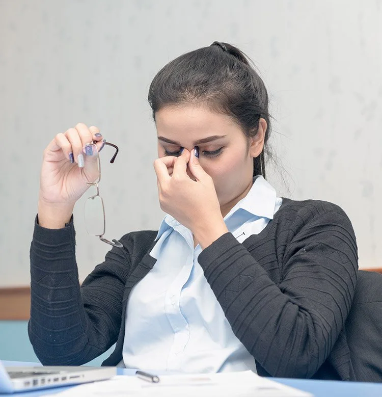 A senior man sitting on the sofa taking his eyeglasses off due to dry eyes
